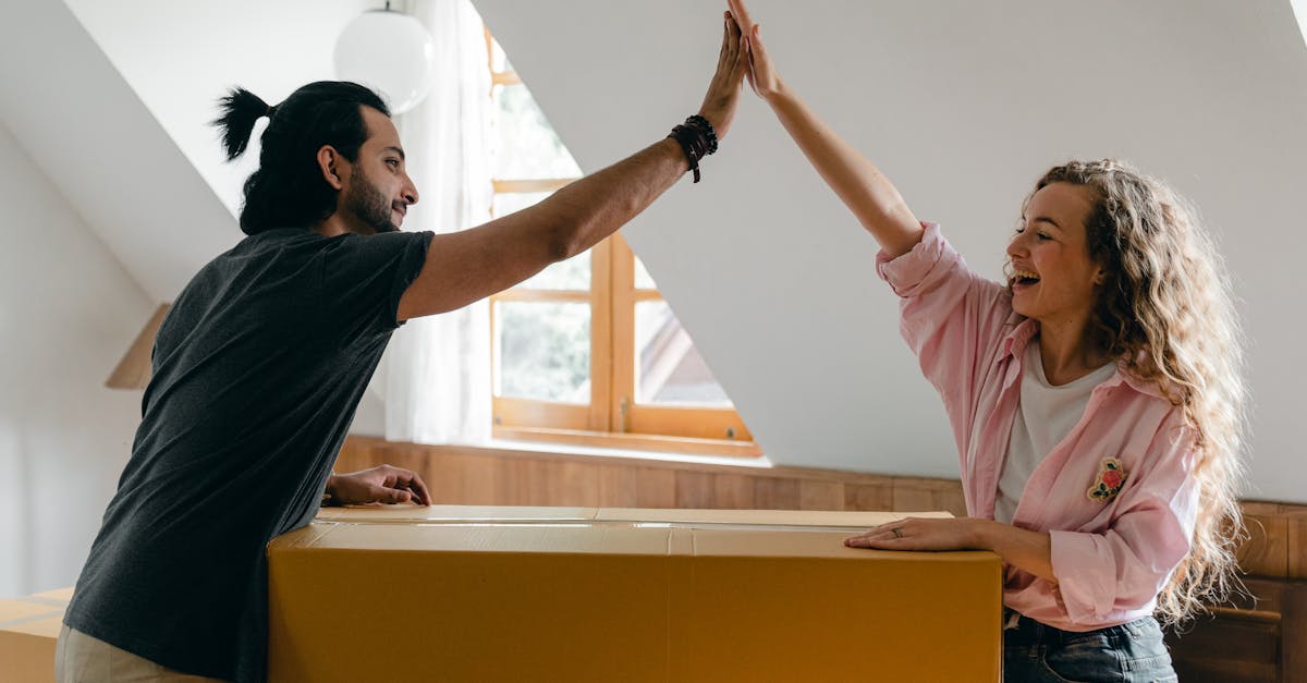Young couple high-fiving in their new home, happily surrounded by moving boxes.